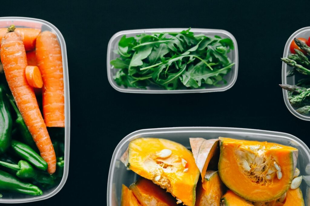 Labeled containers with rice, roasted vegetables, and cooked protein on a kitchen counter